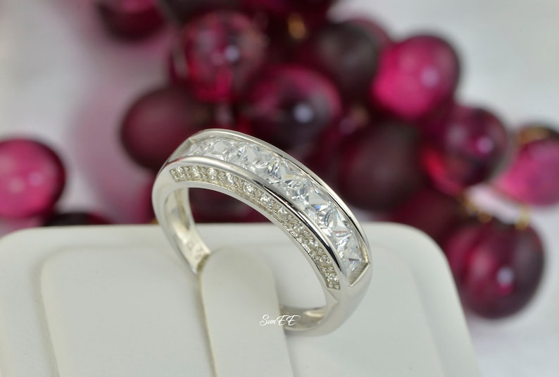 May include: A silver band ring with a row of clear cubic zirconia stones.