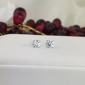 May include: A pair of silver stud earrings with clear round cubic zirconia stones.