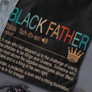 May include: Black Father definition graphic on a black t-shirt. The text is in a rainbow color scheme and reads "Black Father" with a definition below. The definition reads "A man who has stepped up to the challenge of raising his children to be Kings and Queens. Someone who has risen above the negative stereotypes about Black Fathers and is a King in his own right. A provider, a protector, a lover and a strong foundation. Royalty is in his lineage."