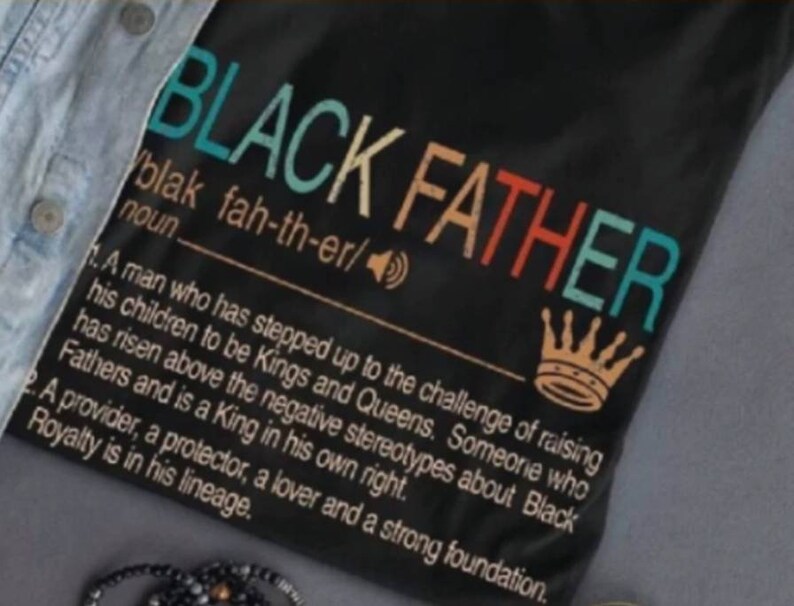 May include: Black Father definition graphic on a black t-shirt. The text is in a rainbow color scheme and reads "Black Father" with a definition below. The definition reads "A man who has stepped up to the challenge of raising his children to be Kings and Queens. Someone who has risen above the negative stereotypes about Black Fathers and is a King in his own right. A provider, a protector, a lover and a strong foundation. Royalty is in his lineage."
