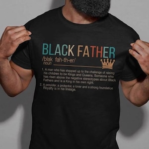 May include: Black Father definition graphic on a black t-shirt. The graphic features a vintage style font and a crown. The definition reads: "A man who has stepped up to the challenge of raising his children to be Kings and Queens. Someone who has risen above the negative stereotypes about Black Fathers and is a King in his own right. A provider, a protector, a lover and a strong foundation Royalty is in his lineage."