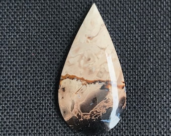 May include: A teardrop-shaped pendant made of brown, white, and black agate with a swirling pattern.