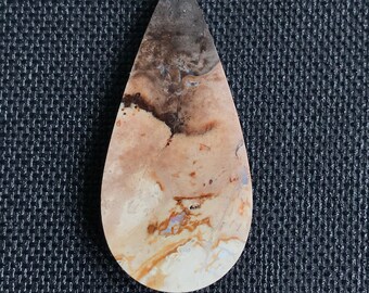 May include: A teardrop-shaped cabochon of brown, white, and orange agate with a swirling pattern.