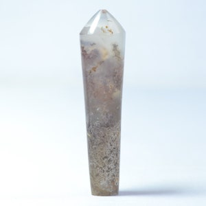 May include: A clear, pointed crystal with brown and white inclusions. The crystal is about 6 inches long and has a smooth, polished surface.
