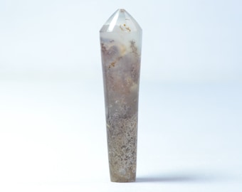 May include: A clear, pointed crystal with brown and white inclusions. The crystal is about 6 inches long and has a smooth, polished surface.