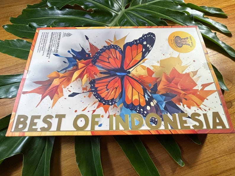 Puede incluir: Una caja con un dise&ntilde;o de mariposa colorida con detalles en naranja, azul y blanco. Las palabras "BEST OF INDONESIA" est&aacute;n en letras doradas. El dise&ntilde;o incluye hojas estilo origami.
