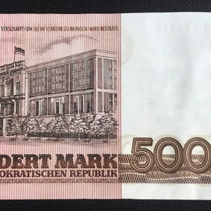 May include: A brown and white banknote with a building on the left side and the number "500" on the right side. The text "UNDERT MARK" and "EN DEMOKRATISCHEN REPUBLIK" is printed on the banknote.