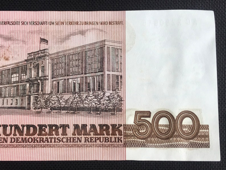 May include: A brown and white banknote with a building on the left side and the number "500" on the right side. The text "UNDERT MARK" and "EN DEMOKRATISCHEN REPUBLIK" is printed on the banknote.