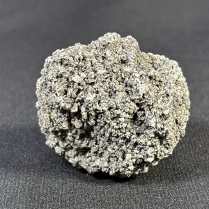 以下が含まれることがあります： 灰色でざらざらした質感の岩のクローズアップ。岩は丸みを帯びており、小さな不規則な破片でできているように見える。