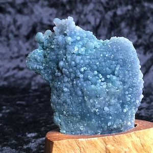 Può includere: Una geode di agata blu e verde con una texture a bolle, esposta su una base di legno.