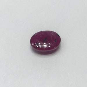 May include: A deep red oval gemstone with black inclusions.