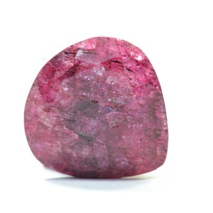 May include: A pink, faceted gemstone with a rough, textured surface.