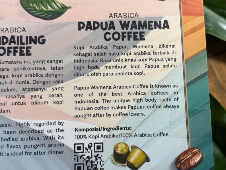 Puede incluir: Anuncio de caf&eacute; con el texto "PAPUA WAMENA COFFEE" en negrita. El texto describe el sabor &uacute;nico del caf&eacute; y su origen en Indonesia. Incluye un grano de caf&eacute; y c&aacute;psulas de caf&eacute;.