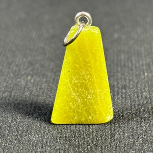 May include: A small, yellow, triangular pendant with a silver bail. The pendant is made of a translucent material with a slightly rough texture.