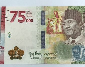 May include: A 75,000 Indonesian Rupiah banknote featuring a portrait of Dr. (H.C.) Ir. Soekarno, the first president of Indonesia, and a train. The banknote also includes the text "75 Tahun Indonesia Merdeka 1945-2020" and the signatures of the Governor of Bank Indonesia and the Minister of Finance of the Republic of Indonesia.