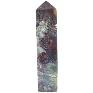 May include: A tall, rectangular crystal obelisk with a pointed top. The stone features a mix of colors, including deep reds, greens, and browns, creating a natural, textured appearance. The obelisk is standing upright against a white background.