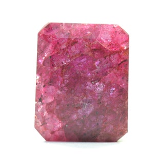 May include: A deep red gemstone with a faceted cut. The gemstone has a rough, textured surface and is a vibrant, rich red colour.