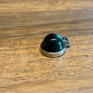 Peut inclure: Un pendentif en argent avec une pierre de malachite verte.