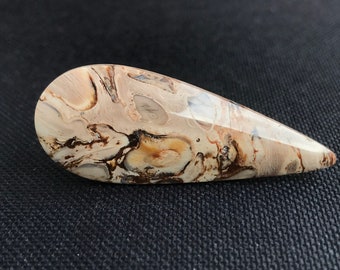 May include: A teardrop-shaped, polished stone with a swirling pattern of brown, white, and beige. The stone has a smooth, glossy finish.