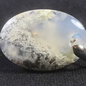 Könnte beinhalten: Ein weißer Achat-Anhänger mit einer silbernen Öse. Der Achat hat ein wolkiges, weißes und graues Muster.