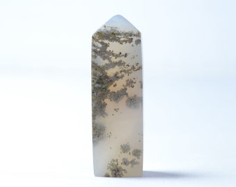 May include: A white and gray agate crystal point with brown and black inclusions. The crystal is polished and has a pointed tip.