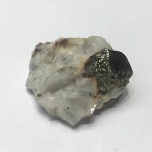 May include: A small, white, crystalline rock with a large, dark gray, metallic pyrite crystal attached to it.
