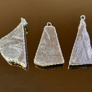 May include: Three triangular pendants with metallic silver surfaces featuring intricate crystalline patterns. Each piece has a textured, irregular edge outlined in a thin gold-toned metal border and includes a small metal loop at the top for hanging.