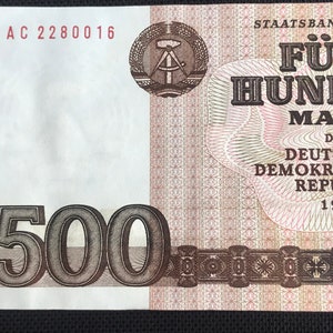 May include: A 500 Mark banknote from the German Democratic Republic, dated 1985. The note features a compass and square, a symbol of the GDR, and the text "STAATSBANK DER DEUTSCHEN DEMOKRATISCHEN REPUBLIK".