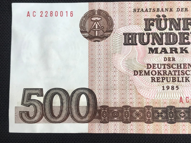 May include: A 500 Mark banknote from the German Democratic Republic, dated 1985. The note features a compass and square, a symbol of the GDR, and the text "STAATSBANK DER DEUTSCHEN DEMOKRATISCHEN REPUBLIK".