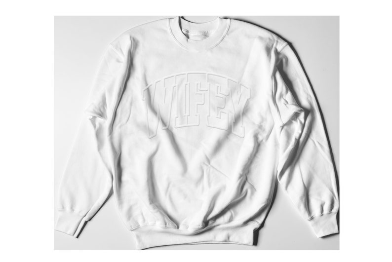 May include: White sweatshirt with a raised, white "WIFEY" graphic on the front.