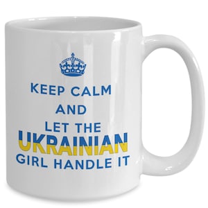 May include: White ceramic coffee mug with a blue crown and the text "Keep Calm and Let the Ukrainian Girl Handle It" in blue and yellow lettering.