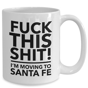 May include: White ceramic mug with a curved handle. The mug features the text "FUCK THIS SHIT!" above the text "I'M MOVING TO SANTA FE" in bold black letters.