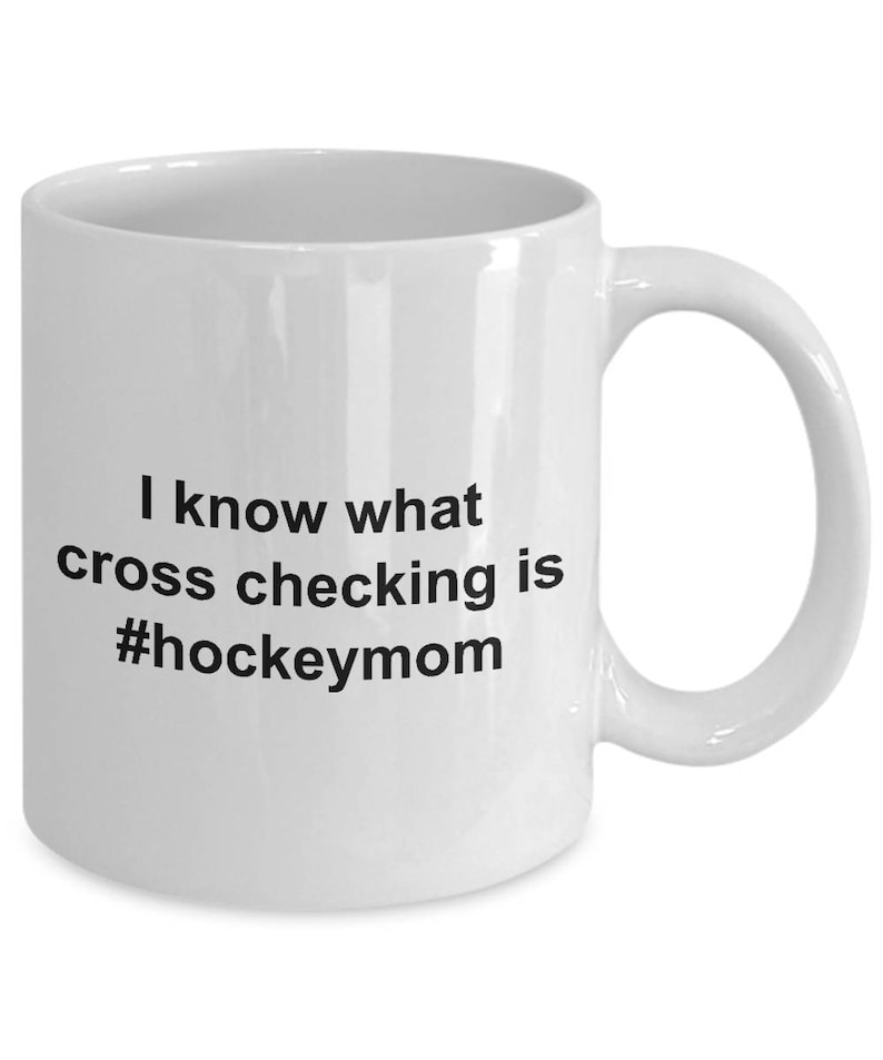 Może przedstawiać: Biały ceramiczny kubek do kawy z czarnym tekstem, kt&oacute;ry brzmi "Wiem, co to jest cross-checking #hockeymom"