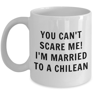 May include: White ceramic mug with a curved handle. The mug features black text that reads: "YOU CAN'T SCARE ME! I'M MARRIED TO A CHILEAN."
