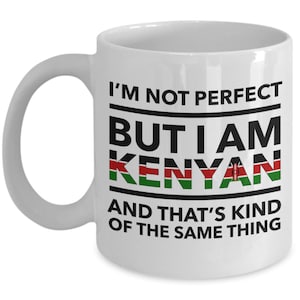 May include: White ceramic coffee mug with black text that reads "I'm not perfect but I am Kenyan" with the Kenyan flag in the word Kenyan. The text continues "and that's kind of the same thing."
