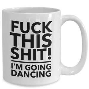 May include: White ceramic mug with the text "FUCK THIS SHIT! I'M GOING DANCING" in bold black letters. The mug has a curved handle and a cylindrical shape, suitable for hot or cold beverages.