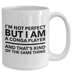 May include: White ceramic coffee mug with black text that reads "I'm not perfect but I am a conga player and that's kind of the same thing."