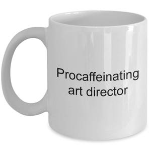 May include: White ceramic coffee mug with black text that reads "Procaffeinating art director".