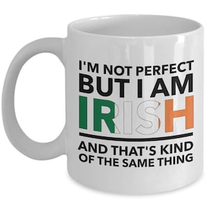 May include: White ceramic coffee mug with a black and green design. The mug reads "I'm not perfect but I am Irish and that's kind of the same thing."