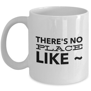 May include: White ceramic coffee mug with a black graphic that reads "There's no place like ~"