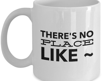 Może przedstawiać: Biały ceramiczny kubek do kawy z czarnym nadrukiem "There's no place like ~"