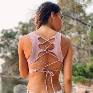 May include: A dusty rose tank top with a lace-up back detail. The top is cropped and has a relaxed fit.