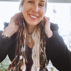 Close-up of natural long feathers on handmade boho feather drop earrings for festival and hippie style