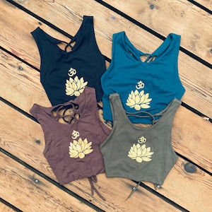 May include: Four tank tops with a gold lotus flower and Om symbol design. The tank tops are in black, teal, brown, and olive green.