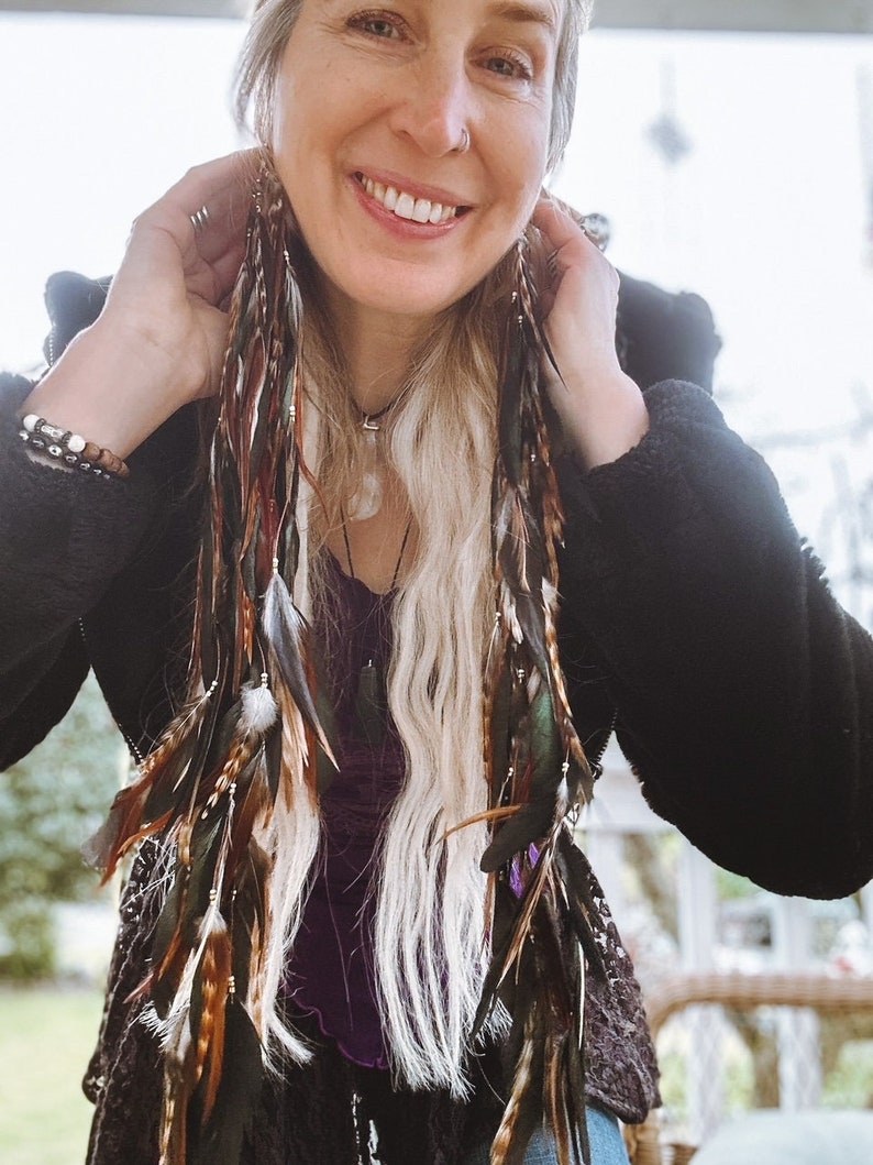 Close-up of natural long feathers on handmade boho feather drop earrings for festival and hippie style