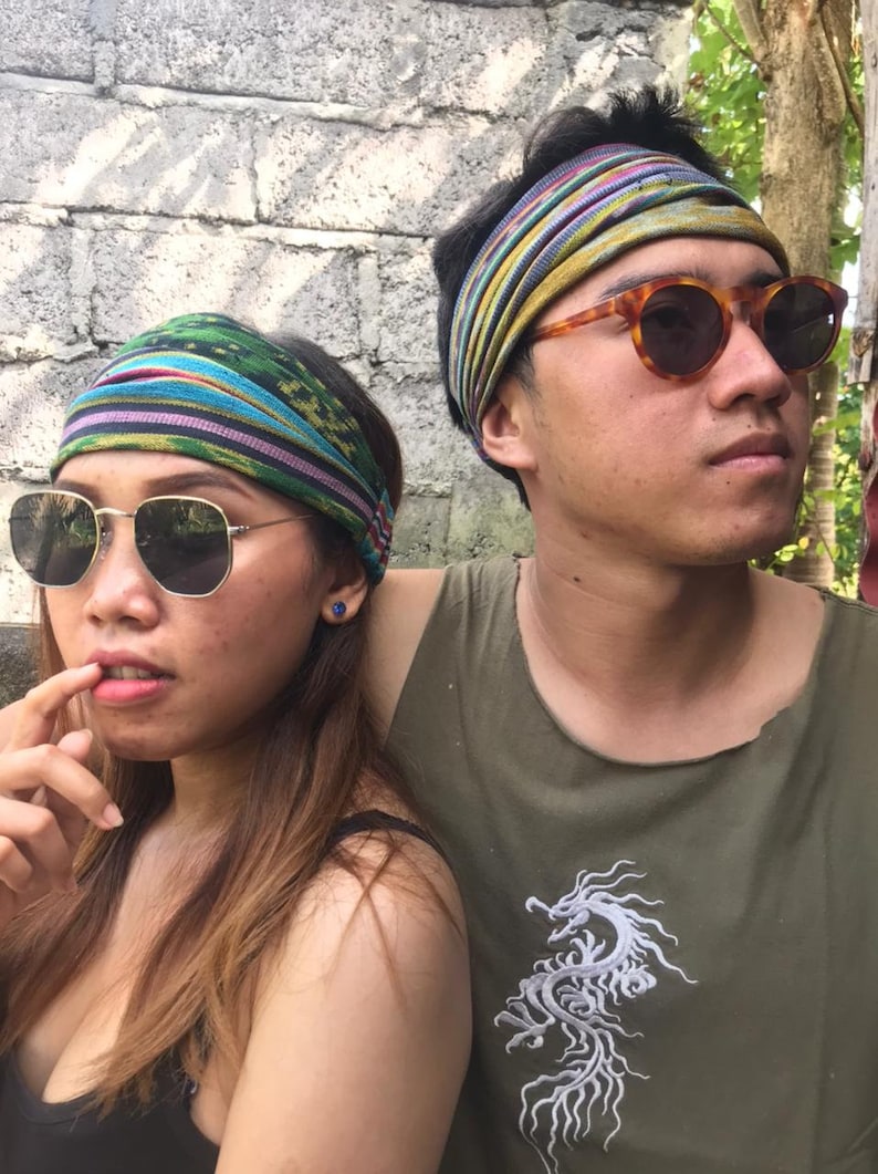 May include: Two people wearing headbands with colorful patterns and sunglasses. The person on the right is wearing a green tank top with a white dragon design.