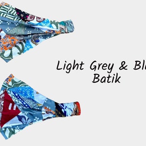 May include: Two light grey and blue batik fabric headbands. The fabric is patterned with a patchwork design.
