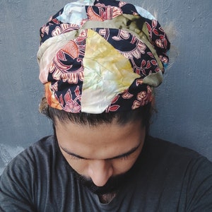 May include: A person wearing a colorful patterned headband with a black and white floral design. The headband is tied in a knot at the top of the head.