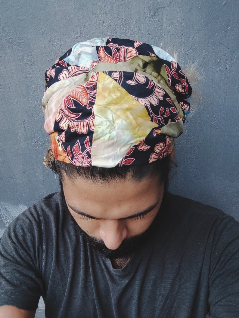 May include: A person wearing a colorful patterned headband with a black and white floral design. The headband is tied in a knot at the top of the head.