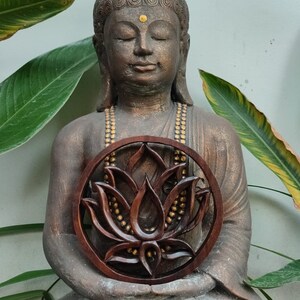 May include: A brown wooden lotus flower carving with gold accents, held by a seated Buddha statue.